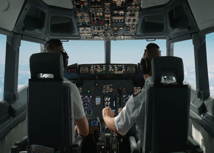 Pilotos de aeronaves comerciais ajustando os parâmetros de voo da aeronave durante o voo em alta altitude. Vista de dentro da cabine