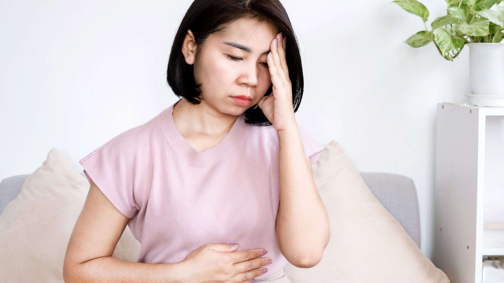 Mulher asiática com dores estomacais causadas por estresse emocional