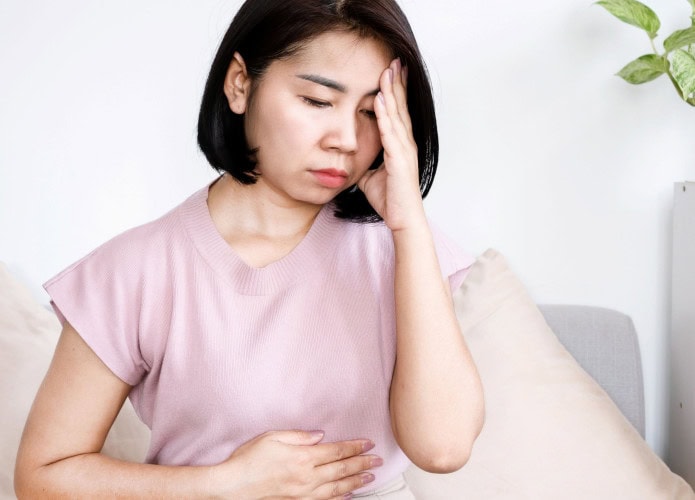 Mulher asiática com dores estomacais causadas por estresse emocional