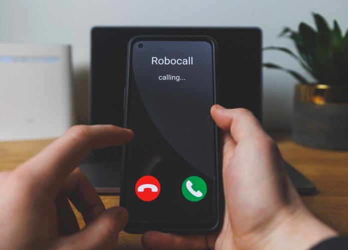 mãos seguram um smartphone com uma chamada de robô aparecendo na tela