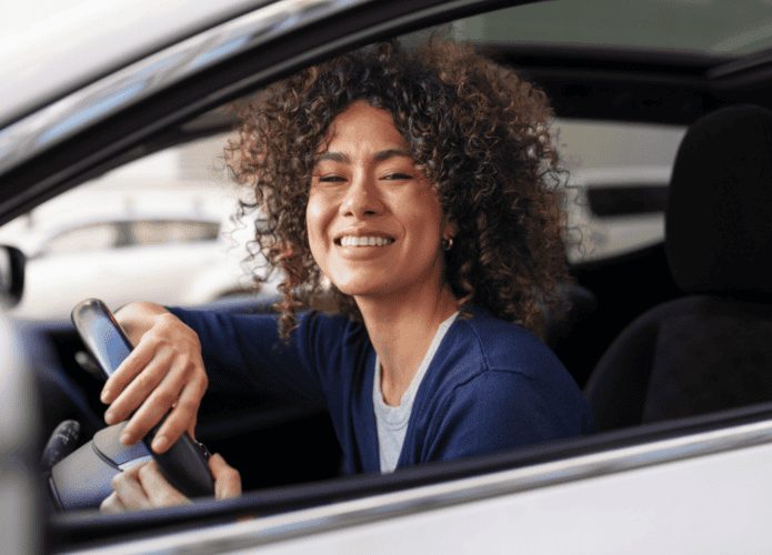 Mulher feliz com o próprio carro assegurado