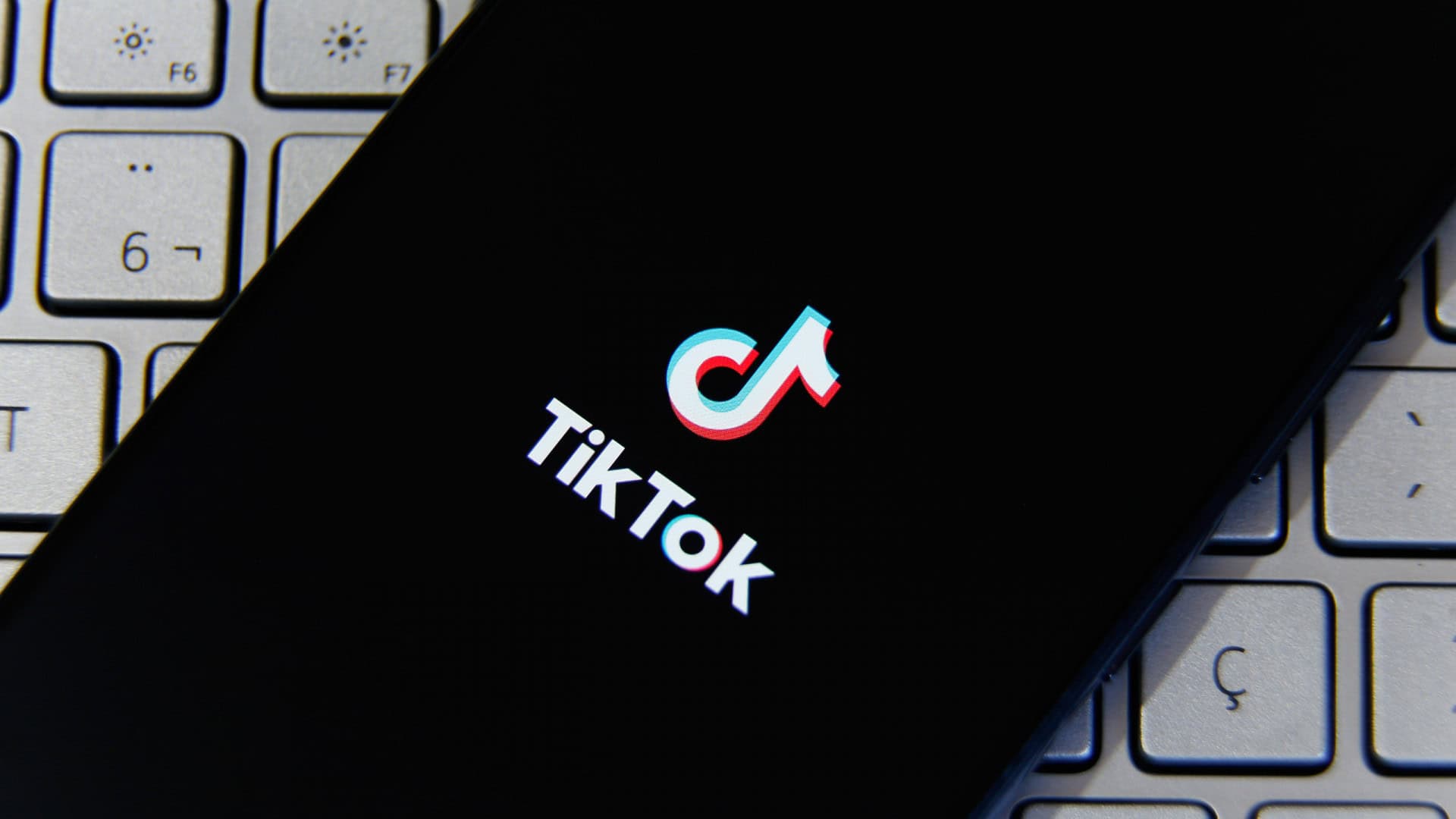 Logo do TikTok em um smartphone que está em cima de um teclado de computador