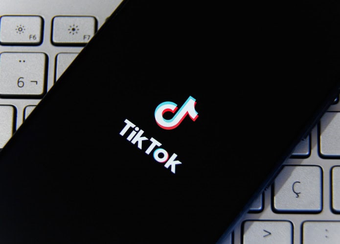 Logo do TikTok em um smartphone que está em cima de um teclado de computador