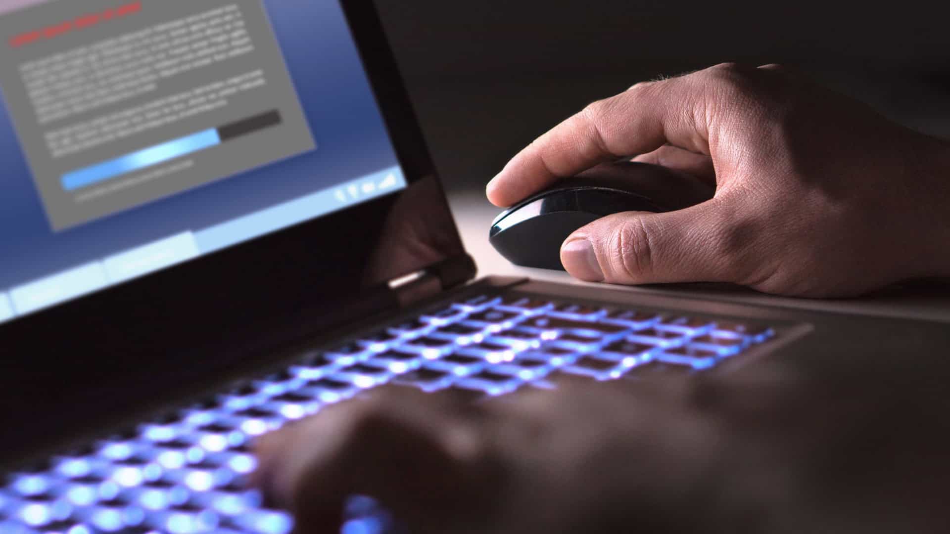 Homem instalando software em laptop no escuro