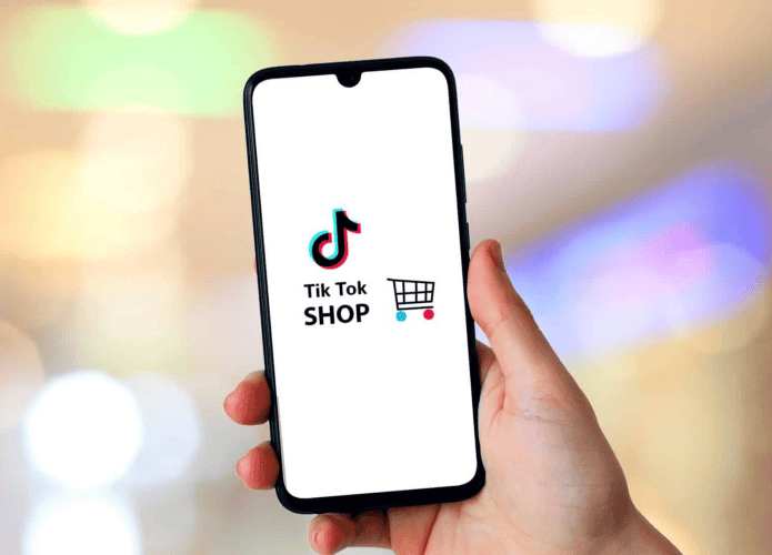 Pessoa segurando o celular e a imagem do TikTok Shop na tela