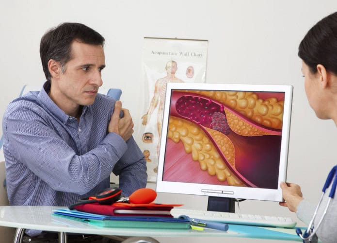 Homem em consulta em uma clínica com sua médica cardiologista vendo o exame na tela do computador.
