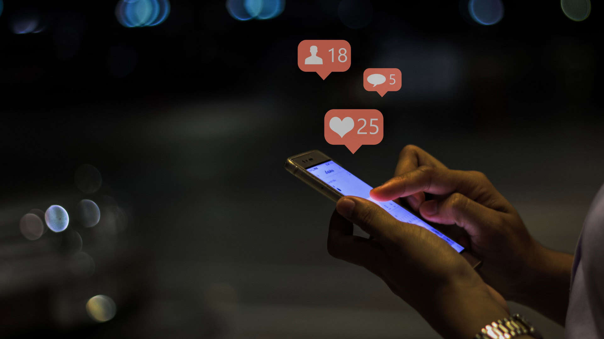 Pessoa mexendo em celular enquanto balões de curtidas, comentários e novos seguidores de redes sociais brotam da tela