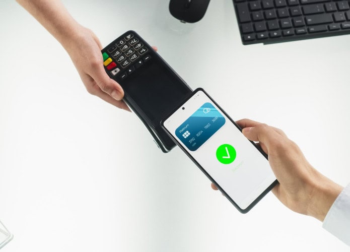 Pessoa pagando por aproximação, por meio de NFC, usando celular em maquininha