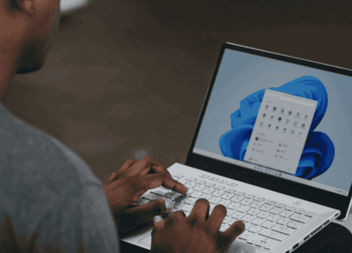 Homem mexendo em um notebook cujo sistema operacional é o Windows