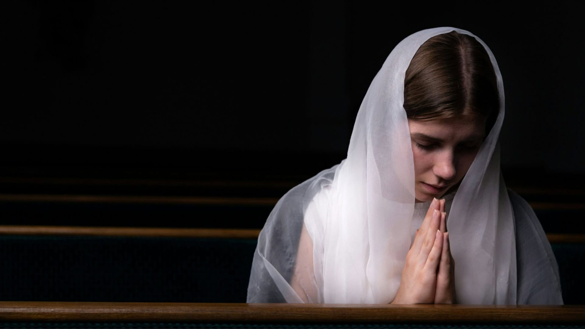 mulher jovem com o véu na cabeça em uma igreja, fazendo oração
