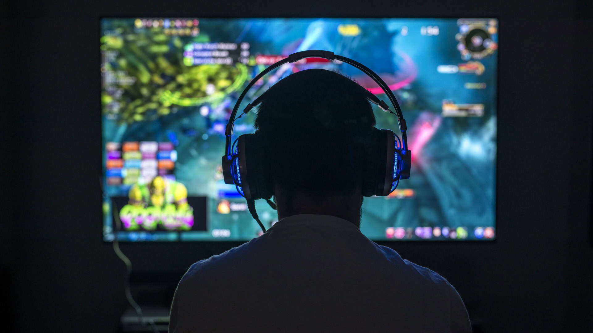 Jovem gamer jogando videogame usando fone de ouvido.