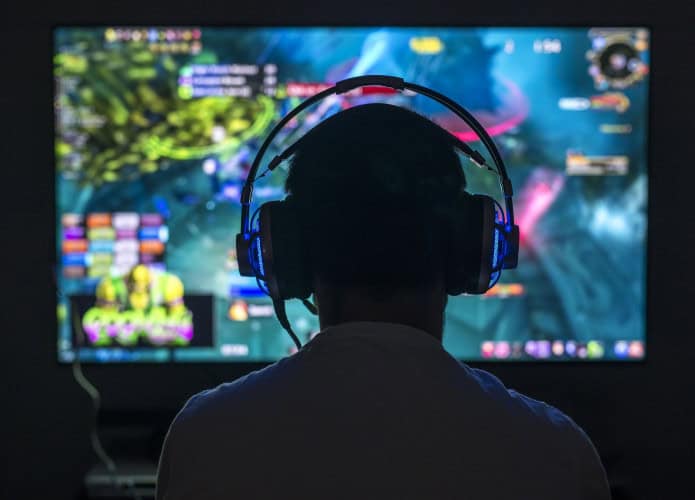 Jovem gamer jogando videogame usando fone de ouvido.