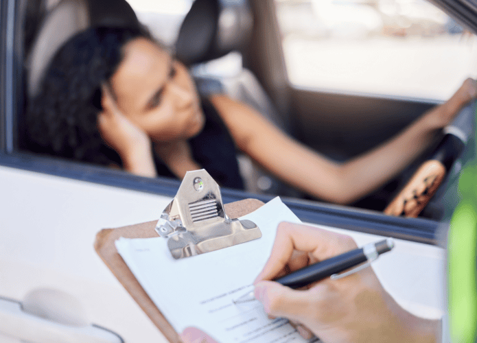 mulher chateado ao volante enquanto um oficial da lei do trânsito lhe escreve uma multa