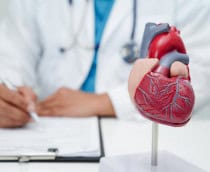 Médico cardiologista com modelo de coração em mesa de clínica