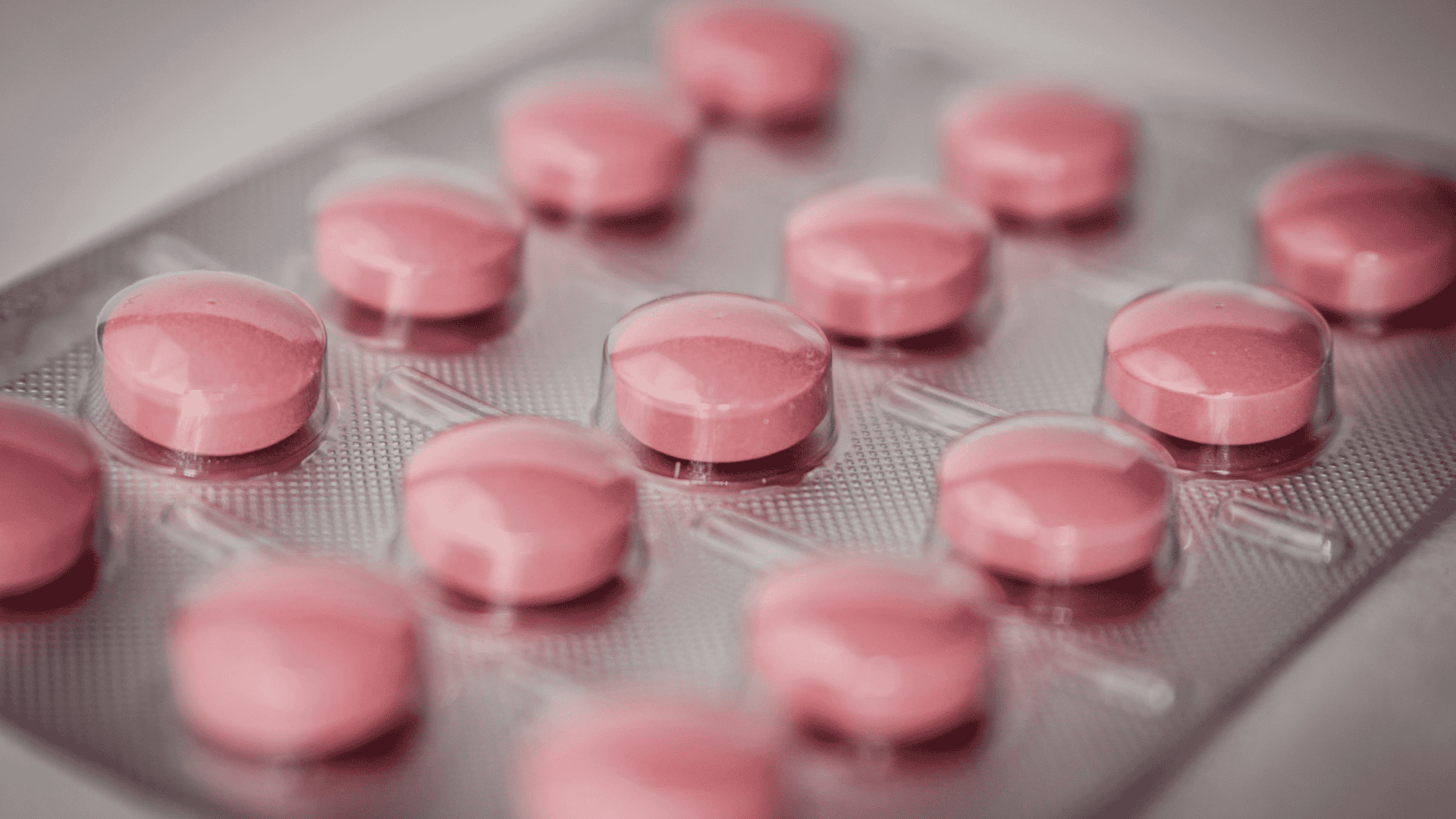 imagem mostra uma cartela de comprimidos cheia de medicações redondas e rosa