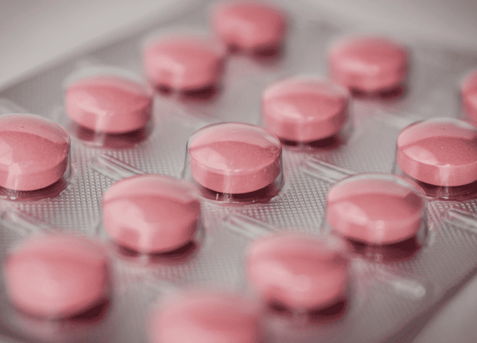 imagem mostra uma cartela de comprimidos cheia de medicações redondas e rosa