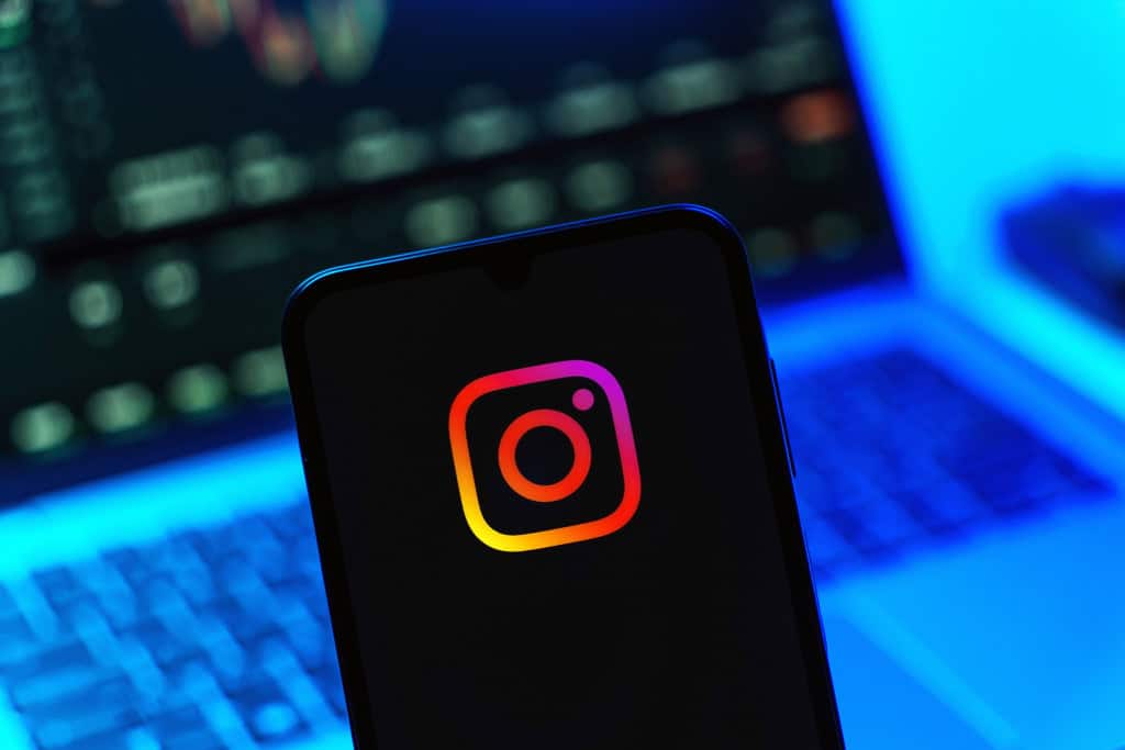 Logo do Instagram em um smartphone com um notebook desfocado ao fundo