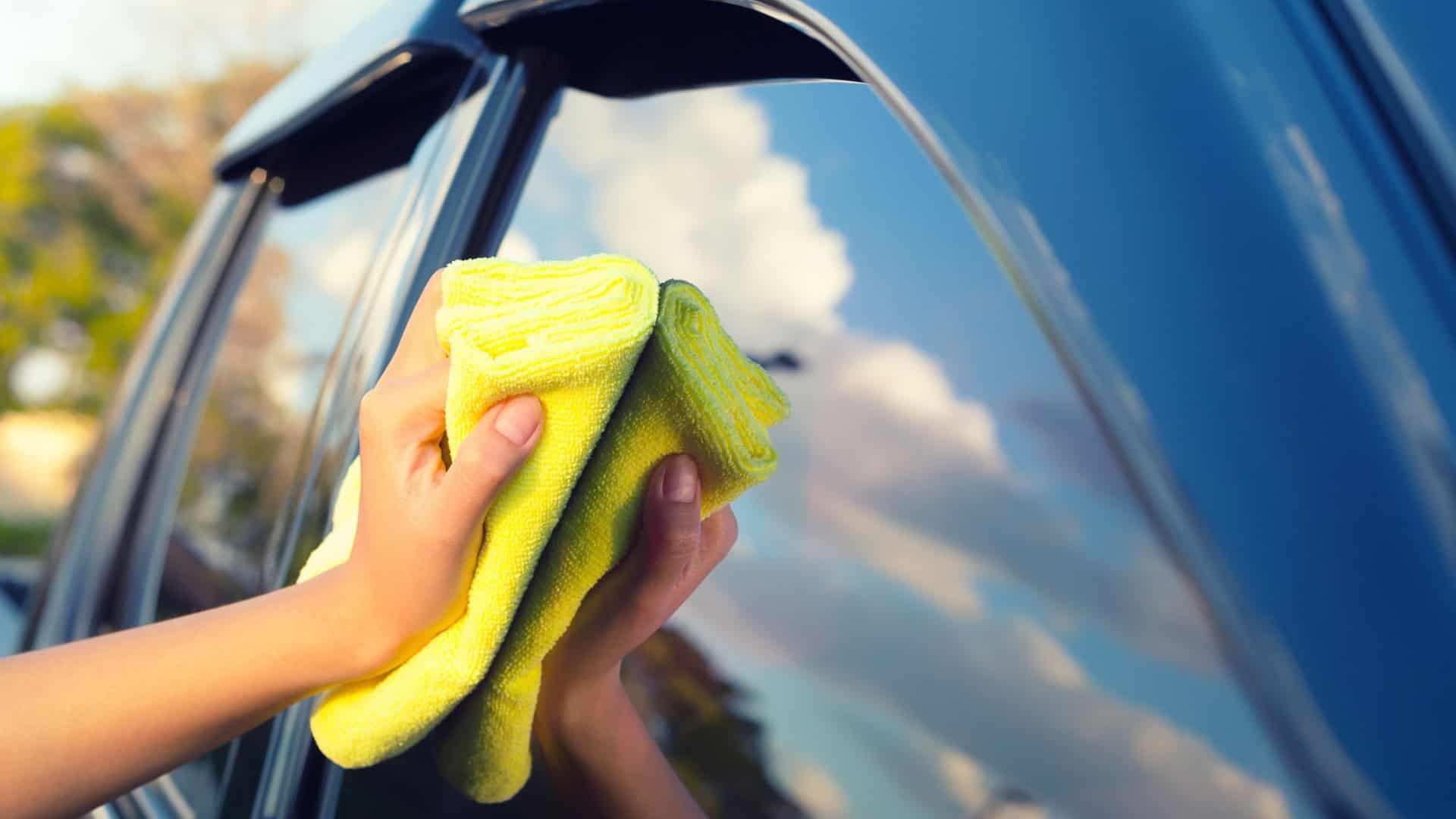 Pessoa passa pano de microfibra em carro em lavagem a seco