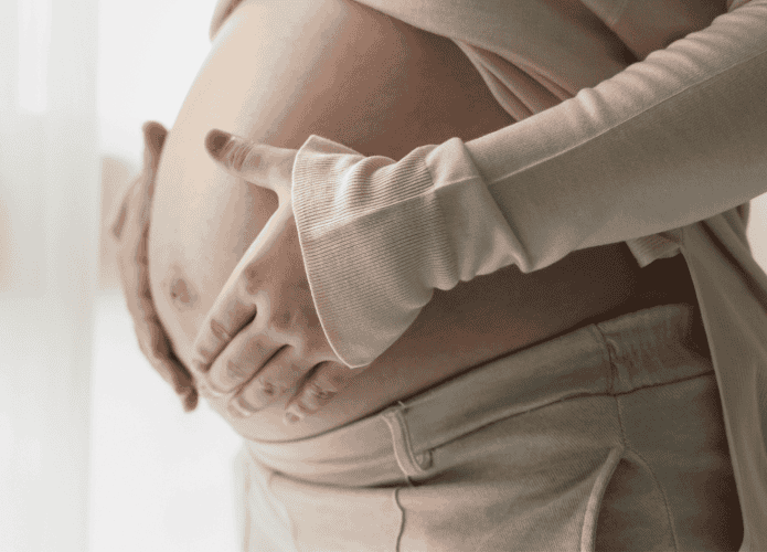 Mulher grávida com as mãos em sua barriga