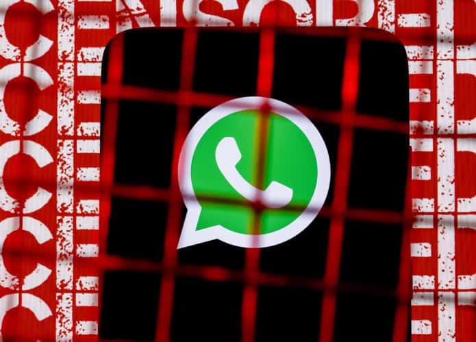 Logo do WhatsApp em um smartphone sendo mostrado atrás de uma cerca de arame