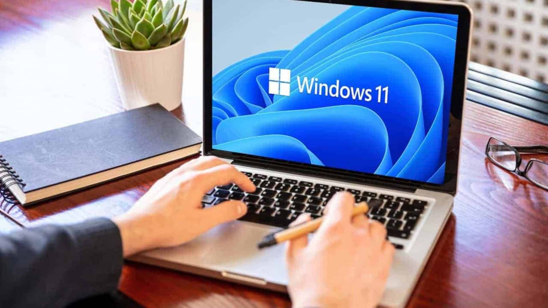 Homem utilizando um notebook com Windows 11 em uma mesa de madeira