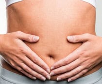 Mulher com as duas mãos sobre a barriga na região do útero e do intestino