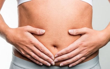 Mulher com as duas mãos sobre a barriga na região do útero e do intestino