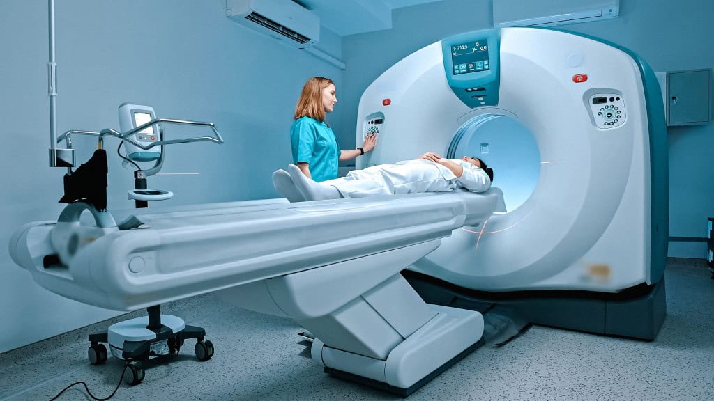 Radiologista conversa com o paciente antes da realização de exames diagnósticos utilizando o aparelho de ressonância magnética no centro médico. 📝 O paciente recebe orientações do médico antes de passar pelo procedimento de tomografia.