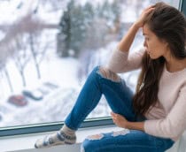 Menina triste deprimida de inverno solitária na janela de casa olhando para o tempo frio chateada infeliz. Sentimentos ruins, estresse, ansiedade, tristeza, emoções