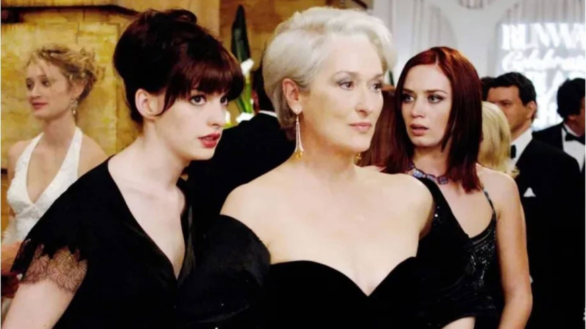 Várias pessoas estão reunidas em um evento formal, vestindo roupas elegantes e sofisticadas. O ambiente tem decoração refinada e iluminação suave, sugerindo uma festa ou cerimônia de alto padrão. Ao fundo, um letreiro iluminado exibe as palavras “RUNWAY Celebrations”, reforçando o clima ligado ao mundo da moda.