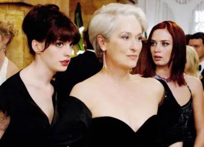 Várias pessoas estão reunidas em um evento formal, vestindo roupas elegantes e sofisticadas. O ambiente tem decoração refinada e iluminação suave, sugerindo uma festa ou cerimônia de alto padrão. Ao fundo, um letreiro iluminado exibe as palavras “RUNWAY Celebrations”, reforçando o clima ligado ao mundo da moda.