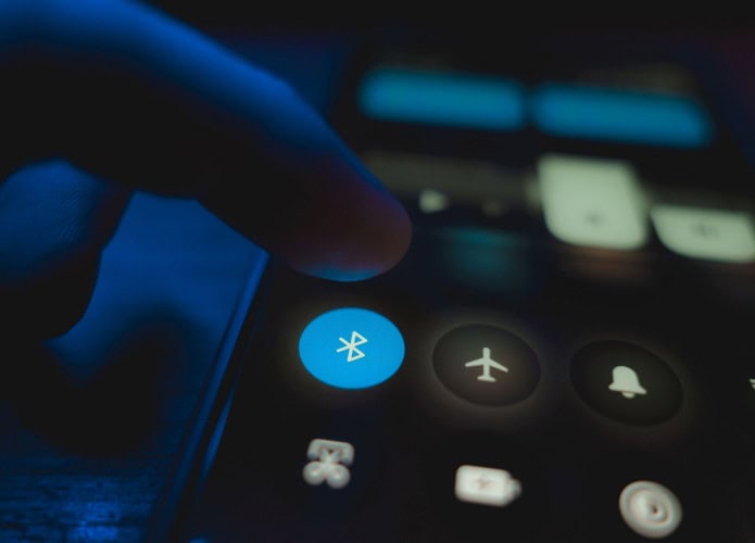 Pessoa com dedo em cima de botão que ativa Bluetooth em celular
