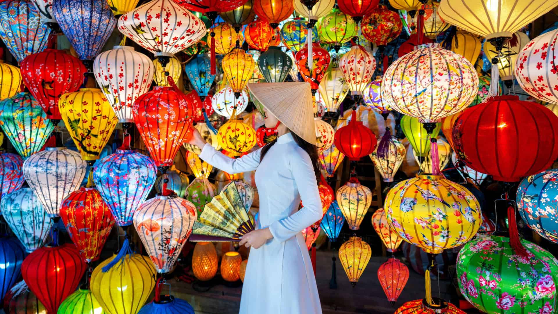 Mulher usando vestido azul e chapéu de palha tocando balão em local cheio de balões com estética chinesa
