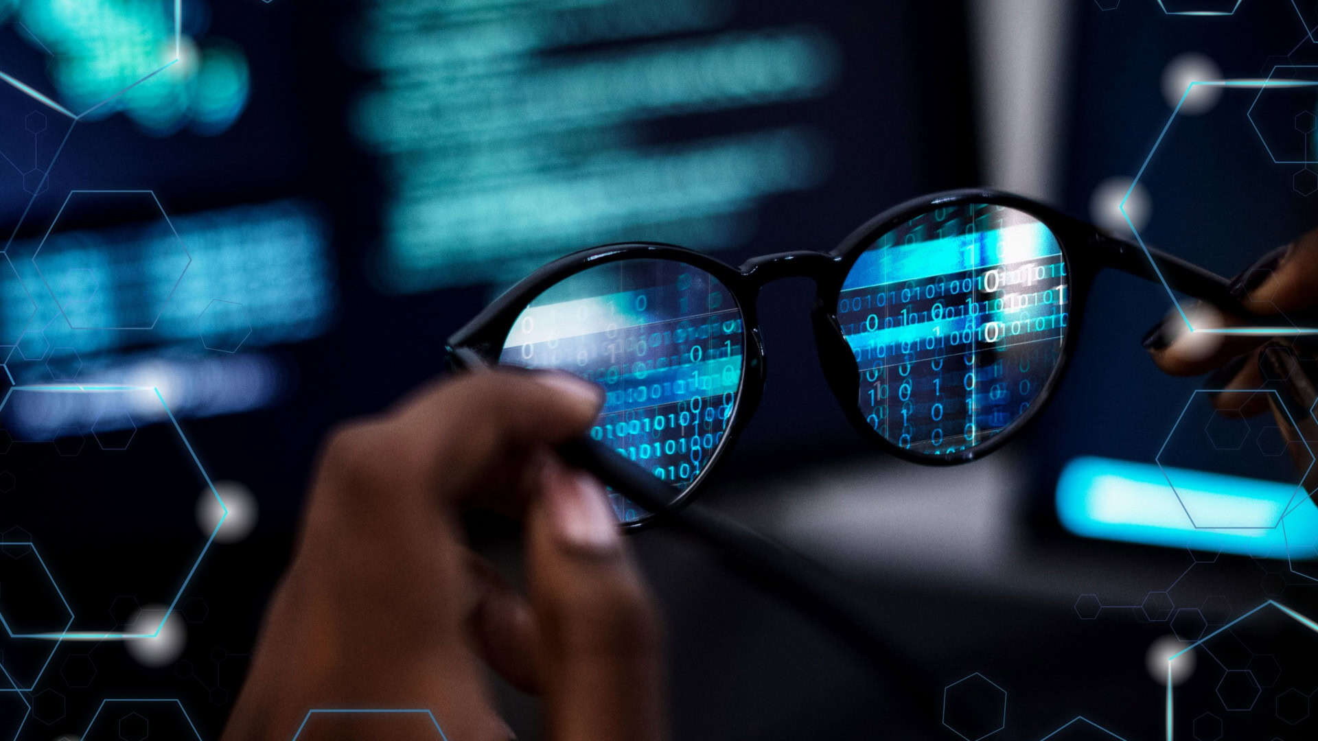 Montagem com pessoa segurando óculos de grau na frente de computador; nas lentes, aparecem códigos binários