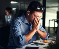 Homem estressado no escritório com rosto enterrado nas mãos