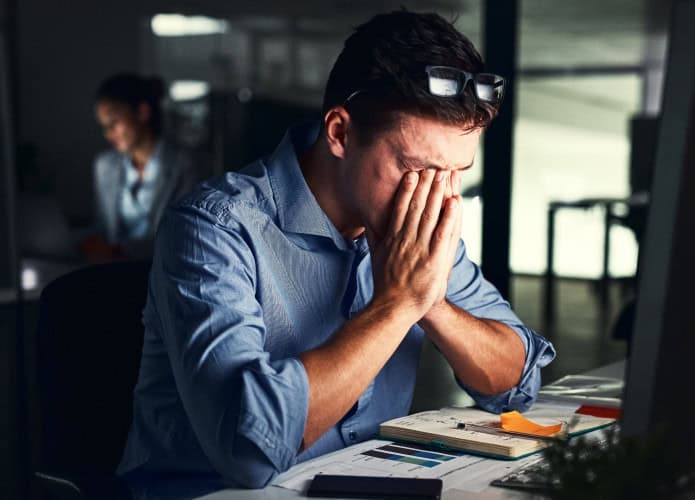 Homem estressado no escritório com rosto enterrado nas mãos