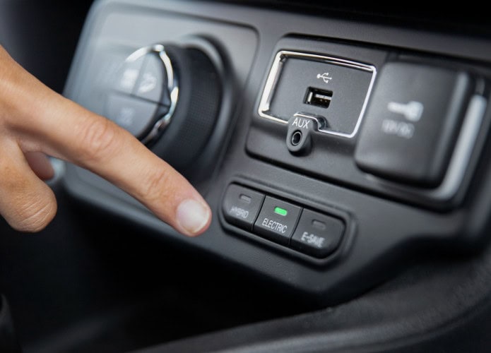 painel de veículo com porta usb visível e motorista ameaçando acionar um botão