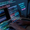 imagem de alguém que digita no computador com telas de códigos flutuantes