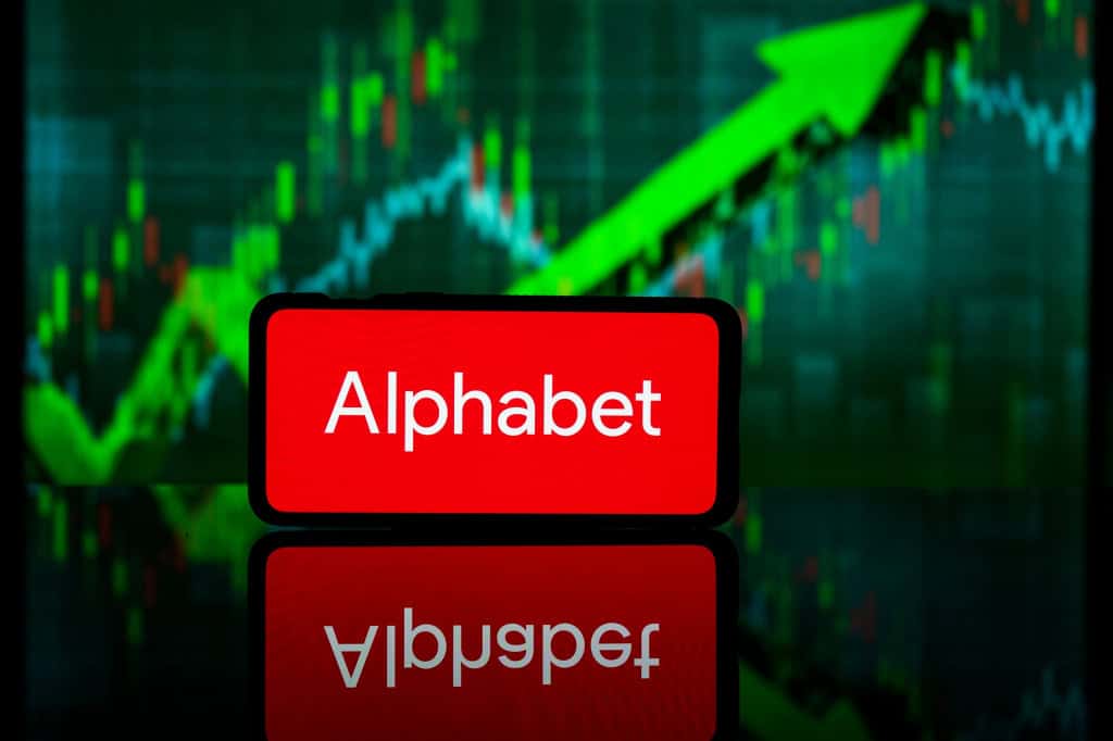 Ao fundo, gráfico financeiro; à frente, logo da Alphabet em um smartphone