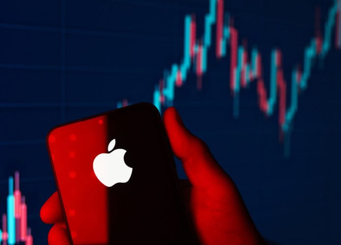 Logo da Apple em um smartphone com um gráfico financeiro ao fundo