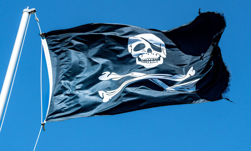 Imagem ilustrativa de bandeira pirata, com símbolizada por um crânio e ossos cruzados