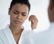 Mulher jovem tentando limpar os ouvidos com cotonete, sente dor e desconforto