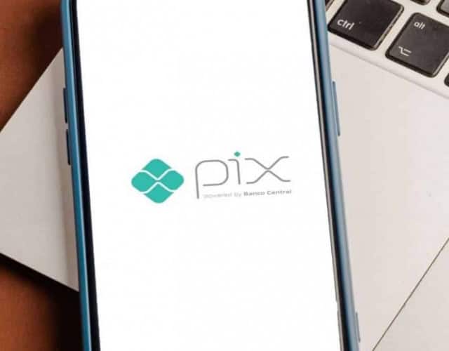 Smartphone em cima de um notebook, no qual vemos o logotipo do Pix