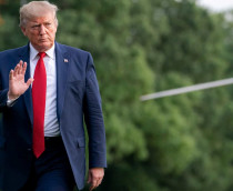 Donald Trump com a mão erguida enquanto anda