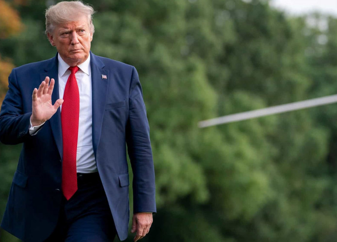 Donald Trump com a mão erguida enquanto anda