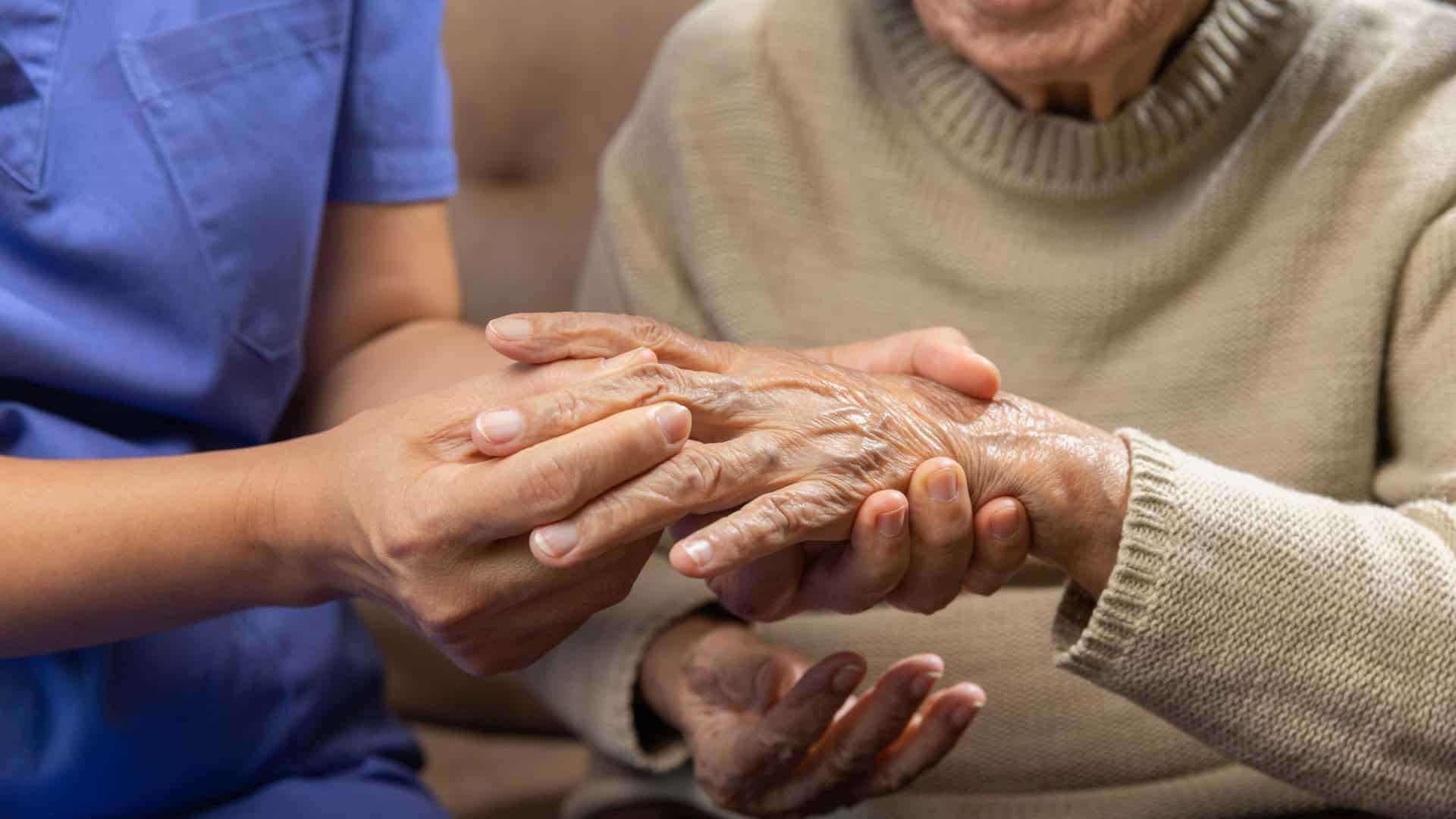 Fisioterapeuta massageia mão de idosa