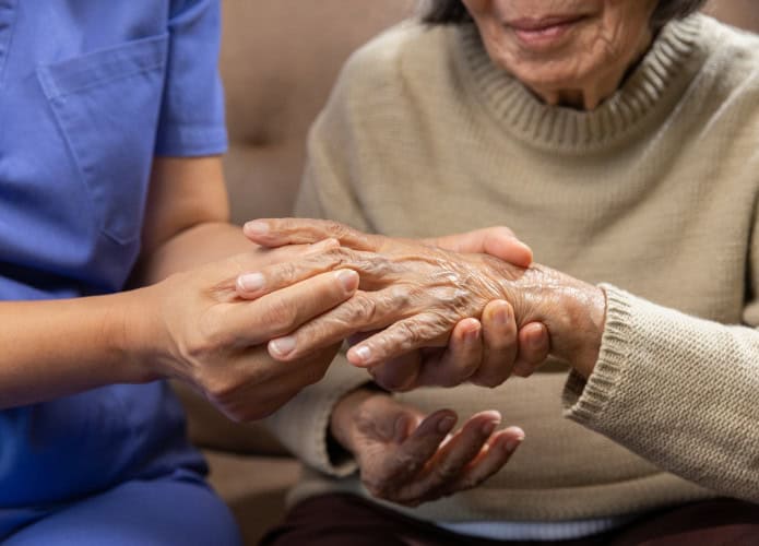 Fisioterapeuta massageia mão de idosa