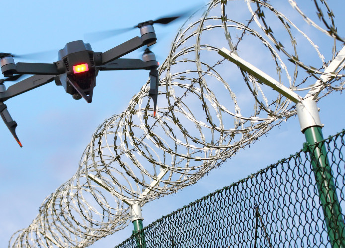 Drone sobrevoando uma cerca de arame farpado