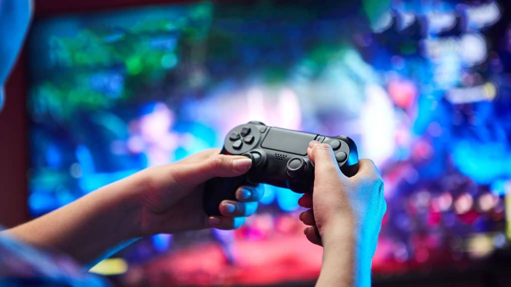 Como montar um PC gamer com sua TV smart na sala de estar 1 Jogador segura controle de videogame em close-up.