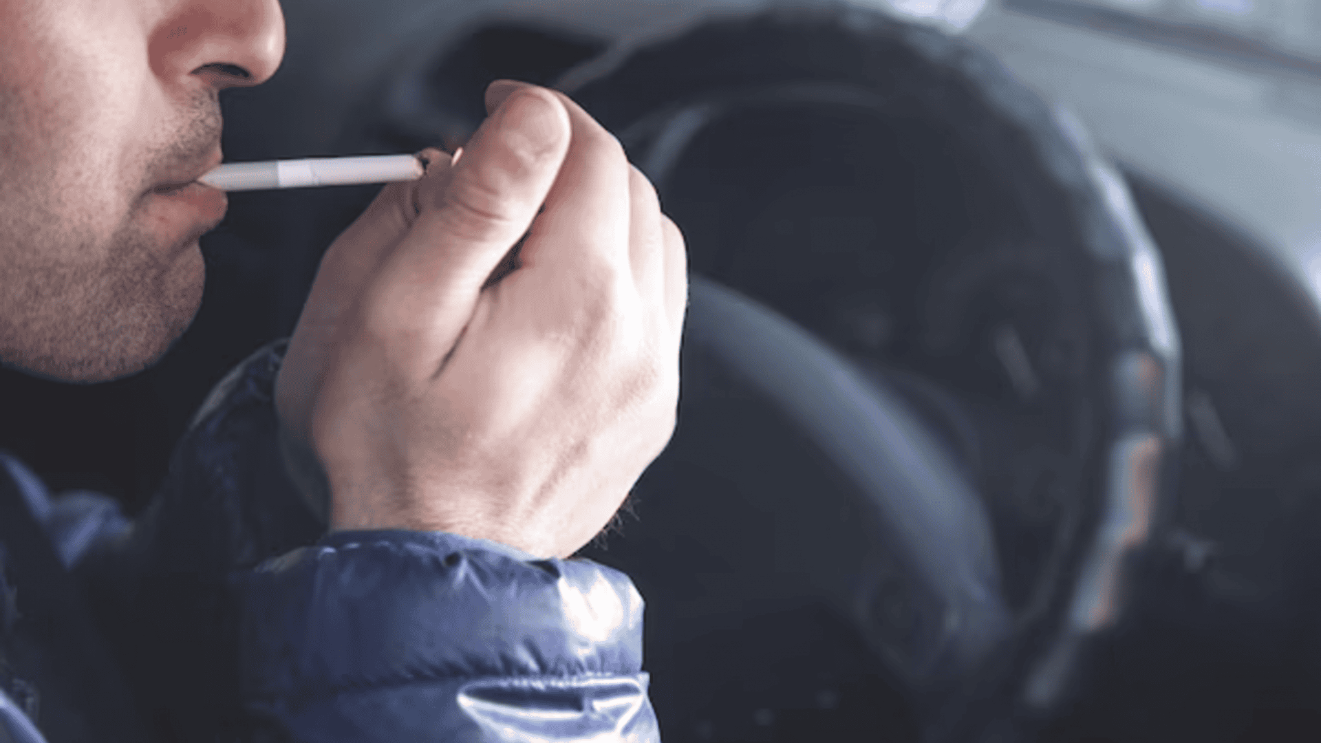 homem fumando um cigarro dentro do seu carro enquanto dirige
